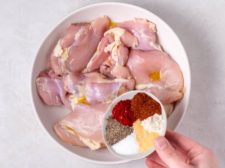 Raw boneless skinless chicken thighs in a bowl with olive oil before seasoning