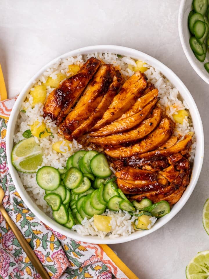 Roasted lime honey chicken thighs served over pineapple coconut rice with quick-pickled cucumbers and fresh lime wedges