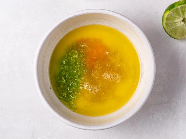 Honey lime sauce ingredients in a bowl with melted butter, lime zest, juice, and hot sauce
