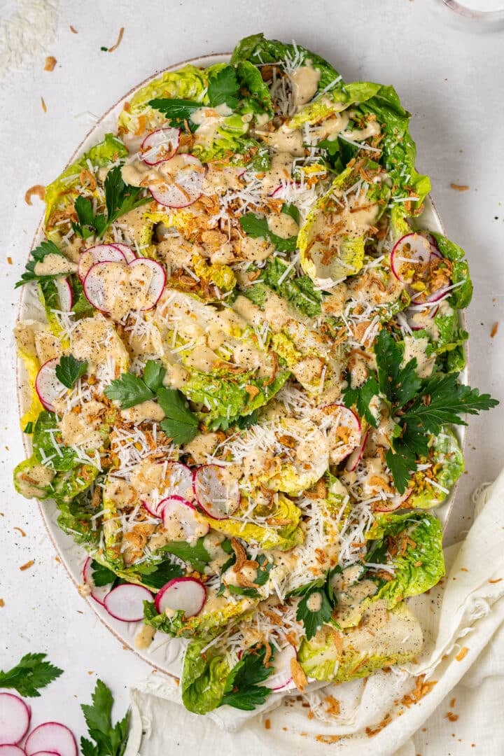 little gem salad recipe with Caesar vinaigrette, parmesan cheese, pistachios, and crispy shallots on platter