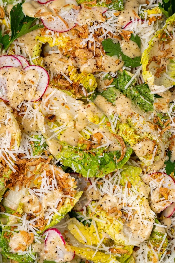 close up of little gem salad with Caesar vinaigrette, parmesan, radishes, and crispy shallots