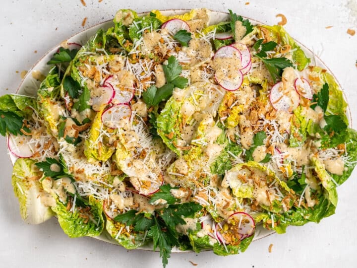 finished little gem caesar salad with vinaigrette, parmesan, radishes, and crispy shallots
