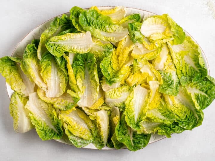 dressed little gem lettuce arranged on platter for Caesar salad