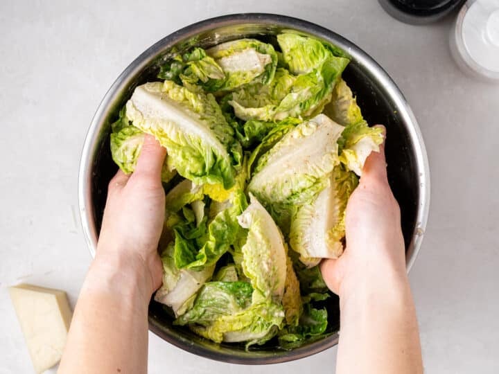 little gem lettuce leaves being tossed in bowl for little gem salad recipe