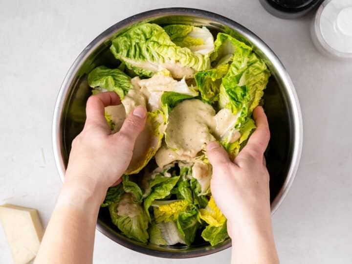tossing lettuce with vinaigrette in mixing bowl