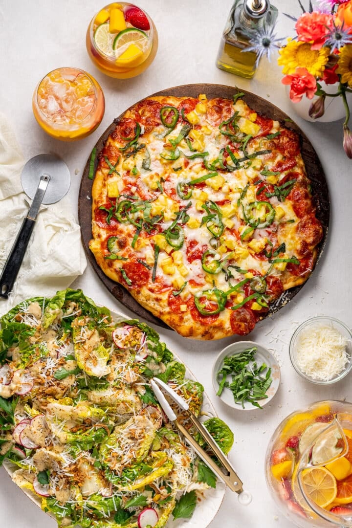 salad recipe with Caesar vinaigrette served with pepperoni pineapple pizza and citrus drinks