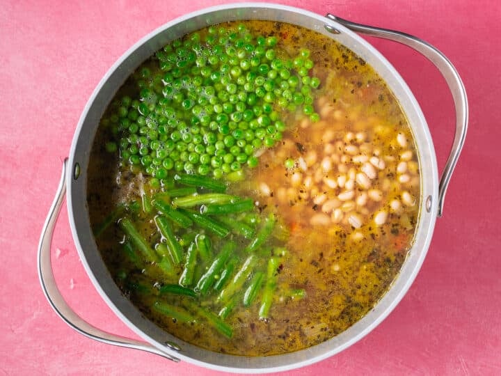 Cannellini white beans, green beans, and frozen peas added to the simmering soup
