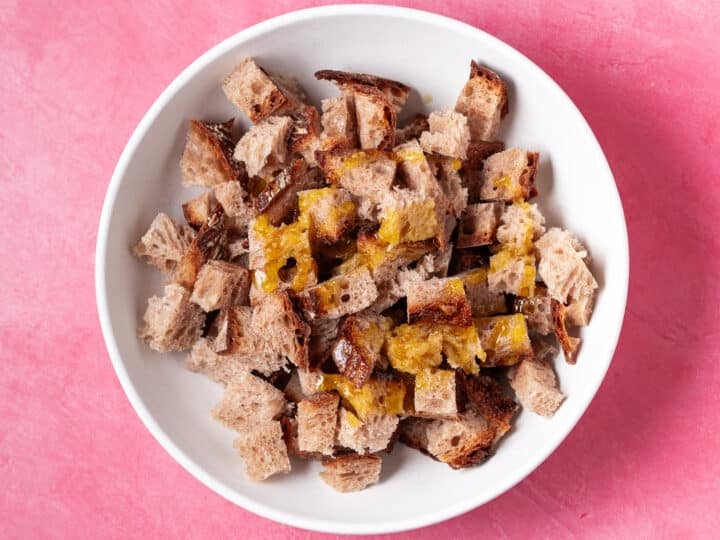 Cubed sourdough bread in a bowl with melted butter and oil for homemade croutons