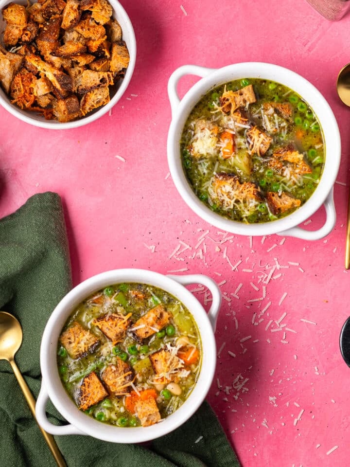 Two bowls of minestrone soup with pesto topped with crispy parmesan croutons