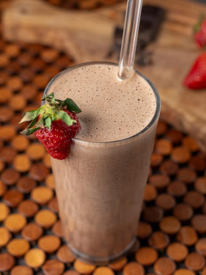 Overhead view of iced mocha protein smoothie with creamy texture and strawberry garnish in a tall glass