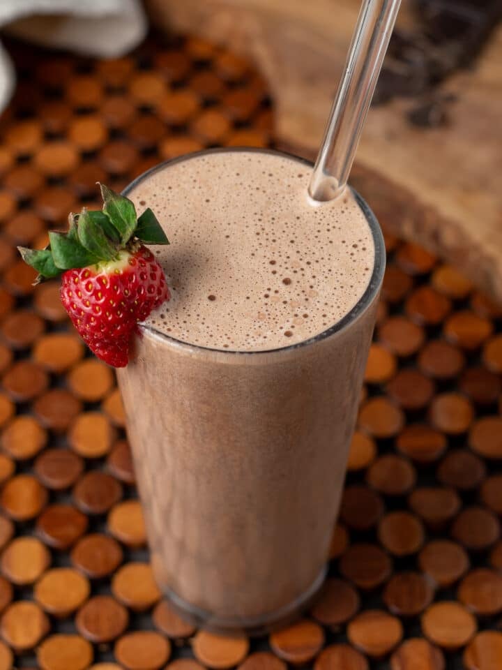 Finished mocha protein shake with strawberry garnish and straw in glass