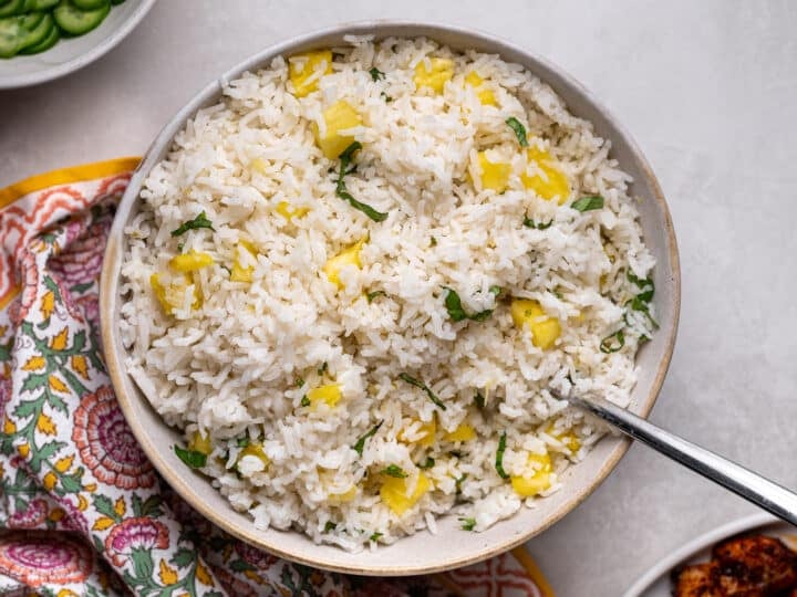 Pineapple coconut rice mixed with fresh pineapple and Thai basil in a serving bowl