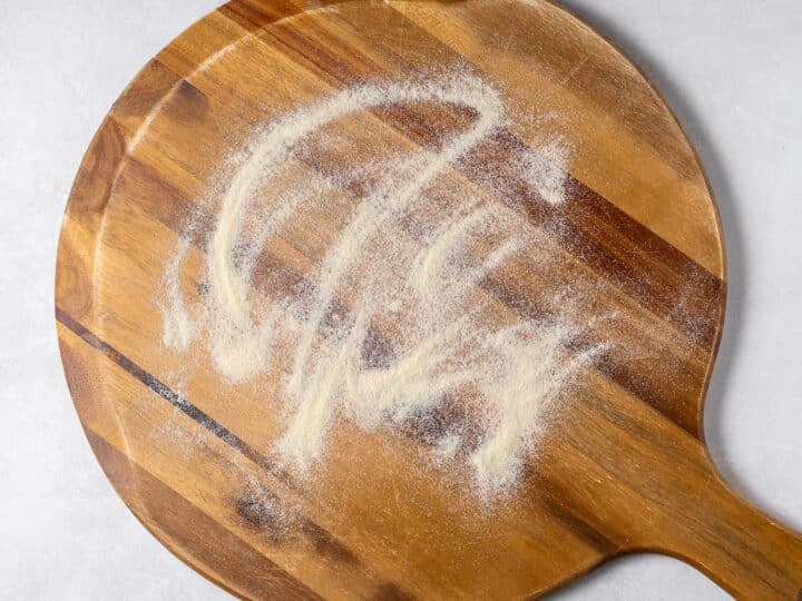 Pizza peel dusted with semolina flour to prevent dough from sticking