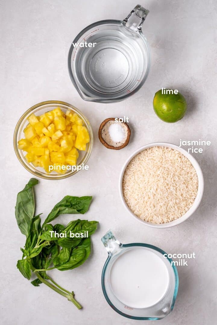 Overhead view of ingredients for coconut lime rice with pineapple, Thai basil, jasmine rice, coconut milk, and lime