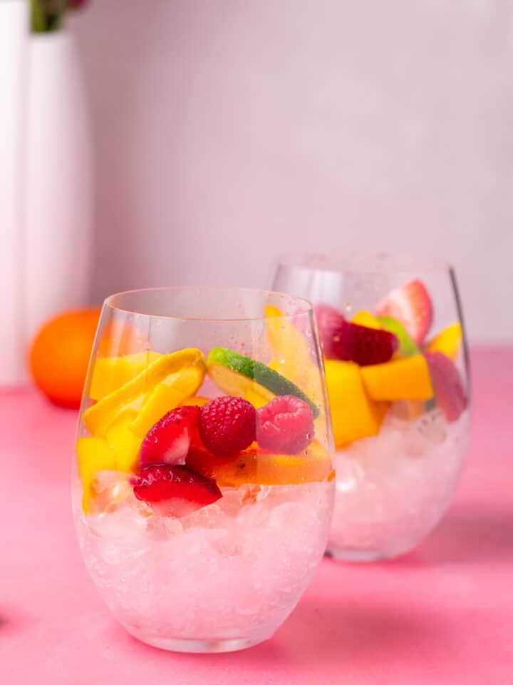 two wine glasses filled with ice and fresh fruit