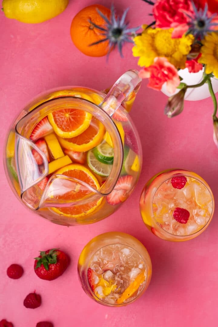 pitcher and two wine glasses filled with ice, fruit and sangria