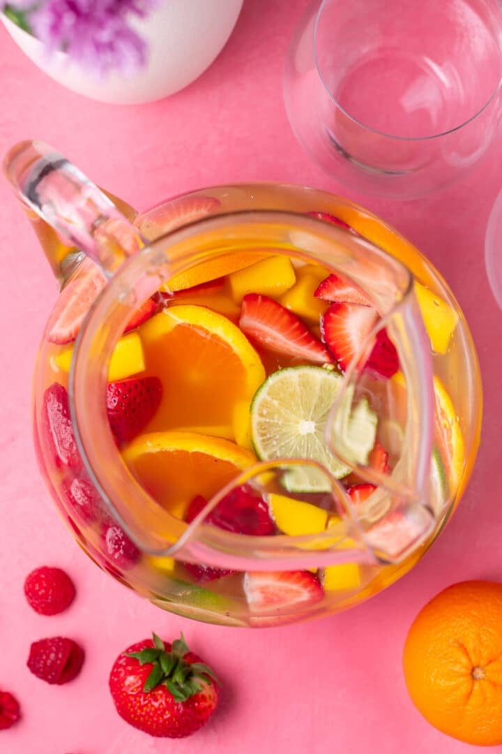 overhead view of a pitcher containing lemon, lime, orange, raspberries, strawberries, mango and sangria