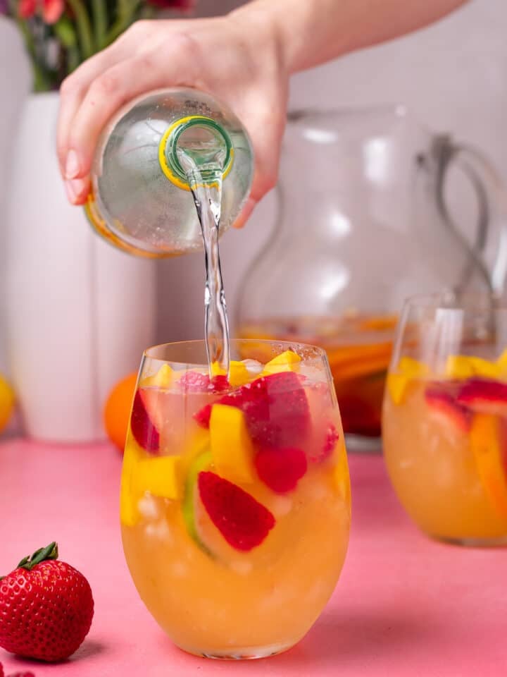 topping glass of sangria off with a splash of sparkling water