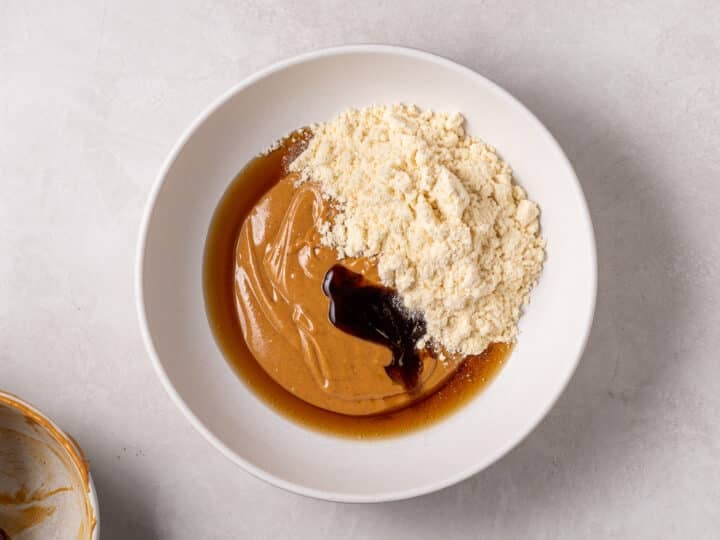 Peanut butter mixture in a bowl with vanilla protein powder, maple syrup, and vanilla extract