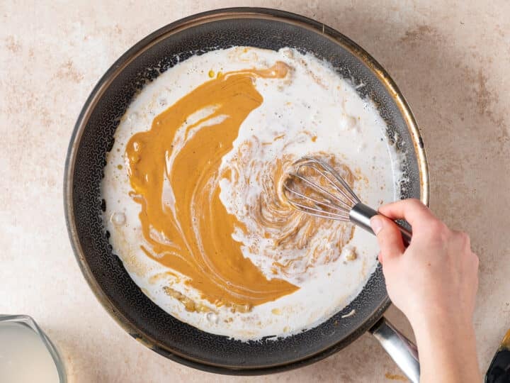 Whisking peanut butter into coconut milk for creamy peanut sauce