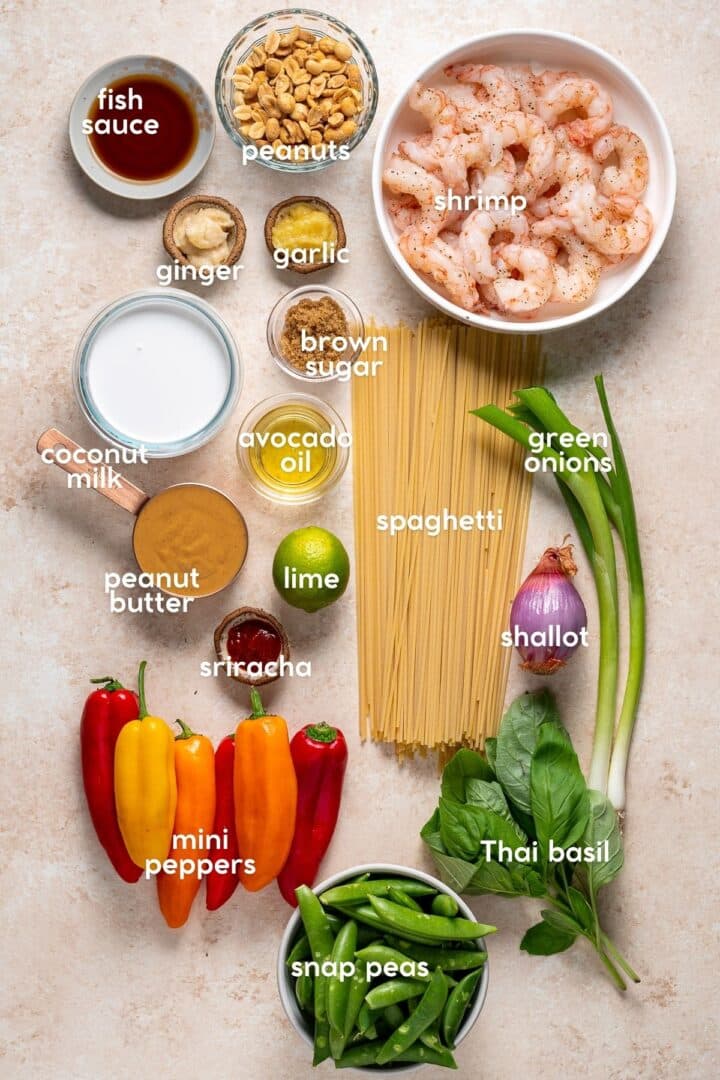 Ingredients for peanut noodles with shrimp including spaghetti, shrimp, peanut butter, coconut milk, snap peas, and Thai basil