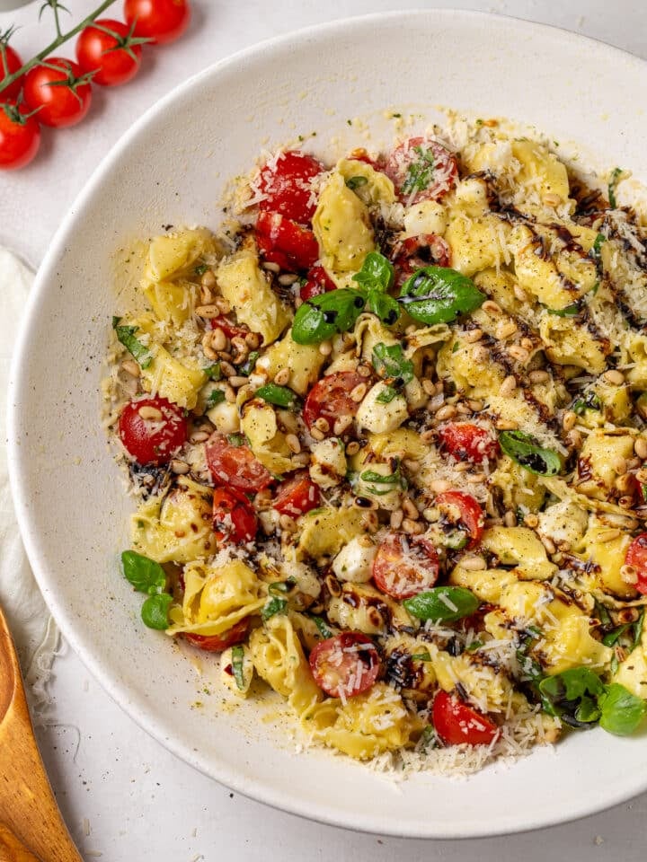 Caprese tortellini salad tossed with cherry tomatoes, mozzarella, basil, pine nuts, parmesan, and balsamic glaze.