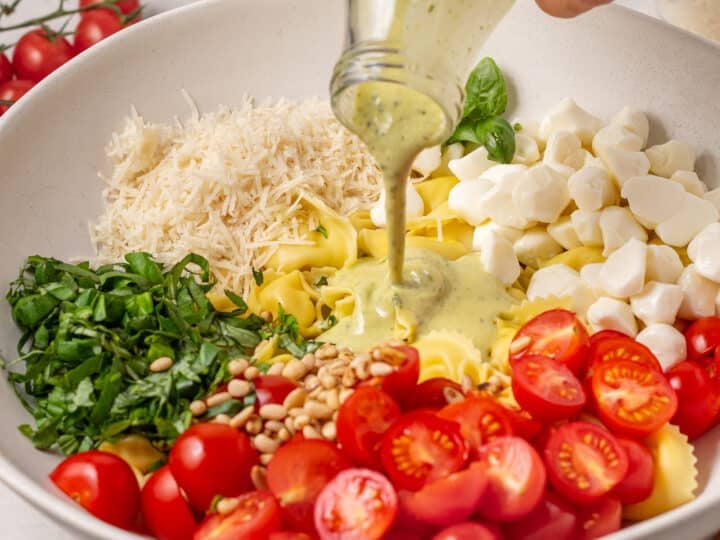 pouring pesto dressing on the salad