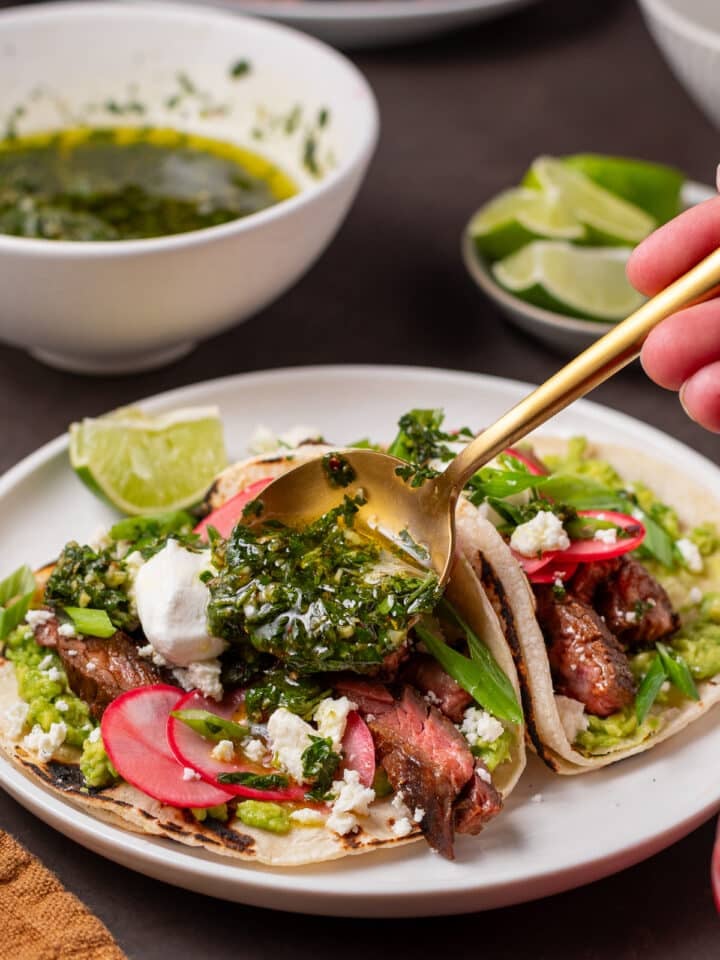 spooning cilantro chimichurri onto steak tacos