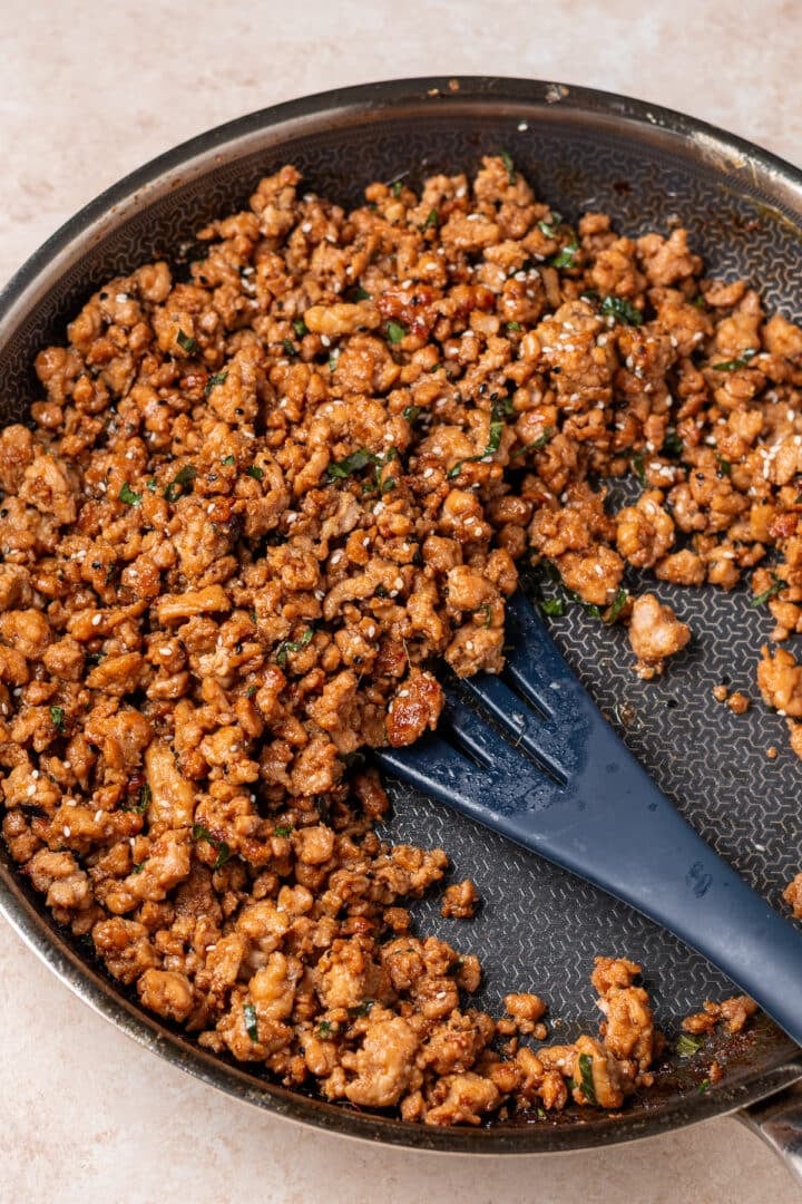 Cooked garlic ginger ground chicken caramelized in a skillet with Thai basil and sesame seeds.