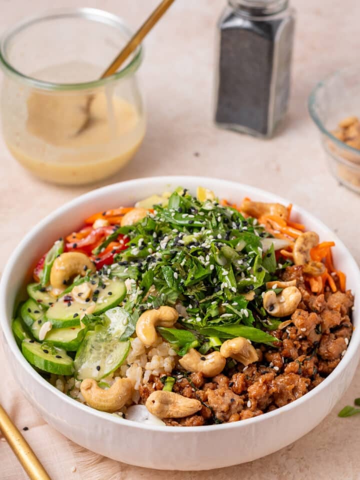 Power bowl with brown rice, cucumber, carrots, cashews, ground chicken, herbs and a creamy dressing.