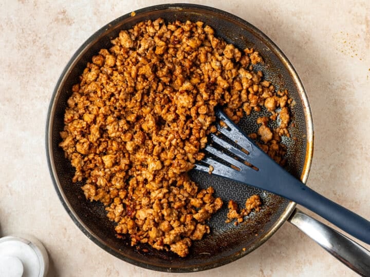 Ground chicken simmering in a glossy garlic ginger sauce with a spatula in the pan.