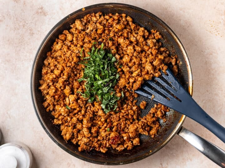 Fresh Thai basil added to the saucy ground chicken before stirring.