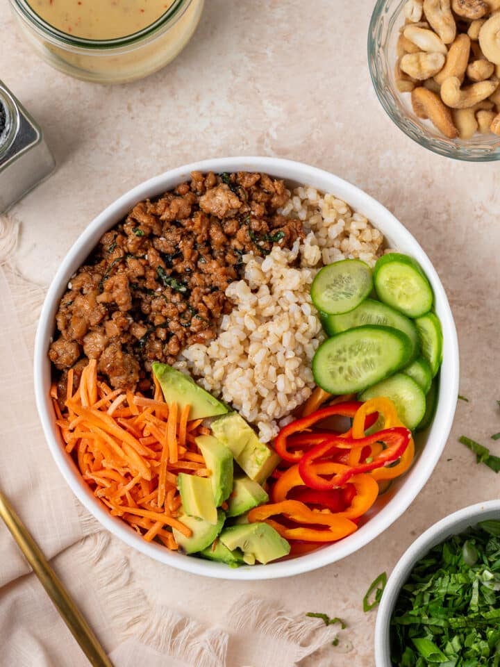 Rice bowl with ground chicken, brown rice, cucumbers, carrots, peppers and avocado.