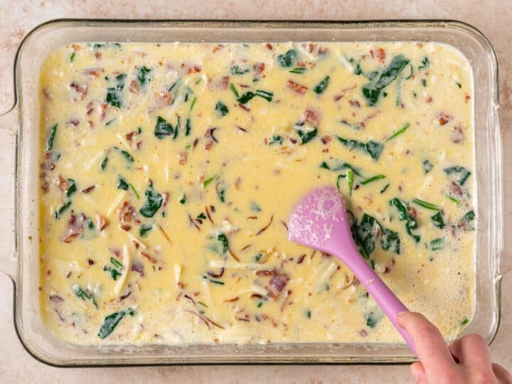 stirring eggs and veggies together in the baking dish