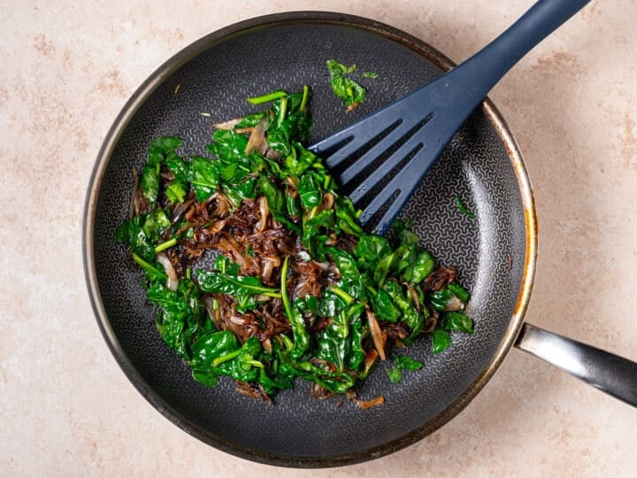 wilted spinach added to the caramelized shallots