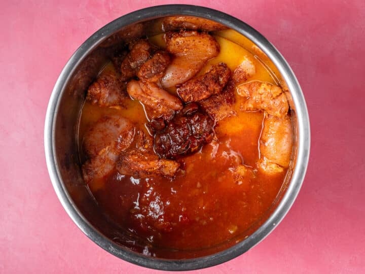 Seasoned chicken thighs with salsa, chipotle peppers, orange juice, and lime juice in an Instant Pot.