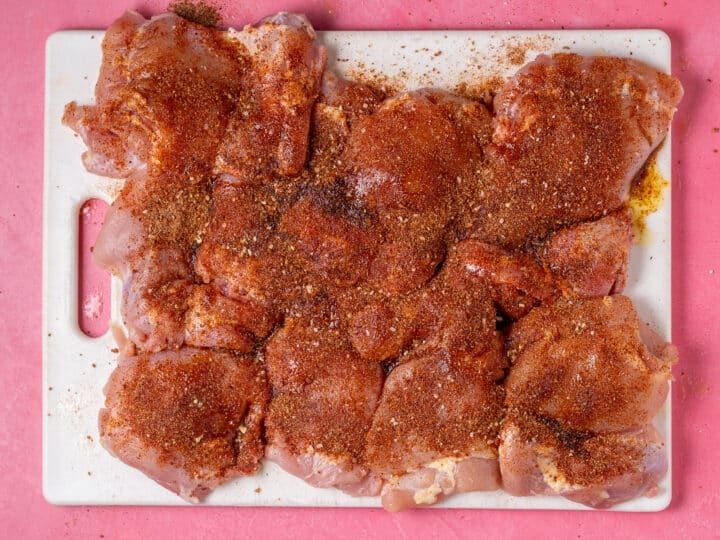 Chicken thighs coated with a seasoning blend before cooking.