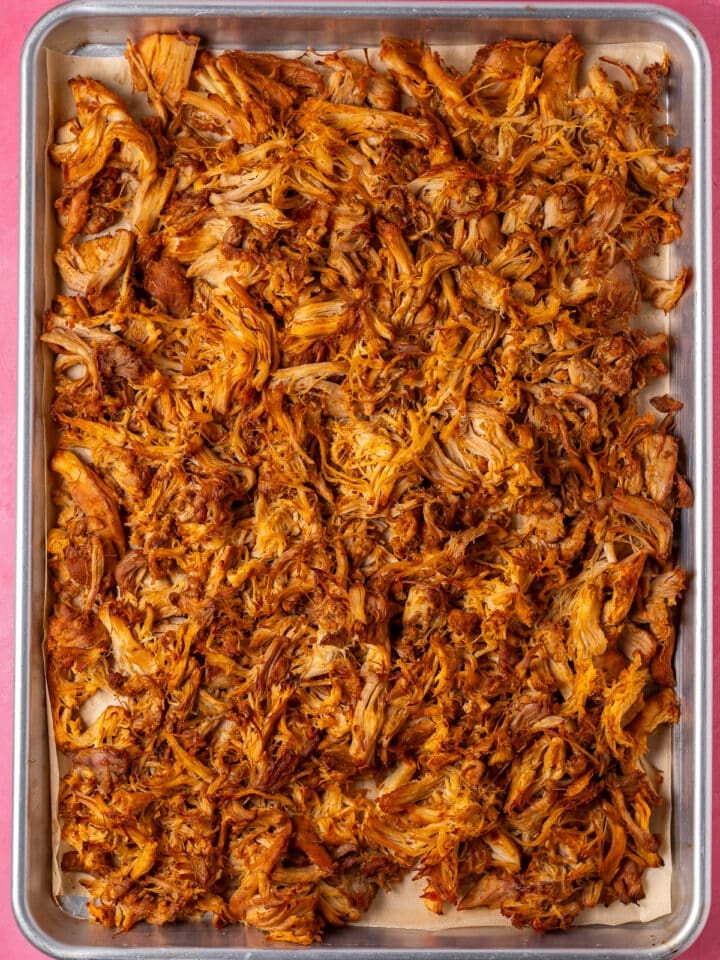 Broiled shredded chicken with crispy golden edges on a sheet pan.
