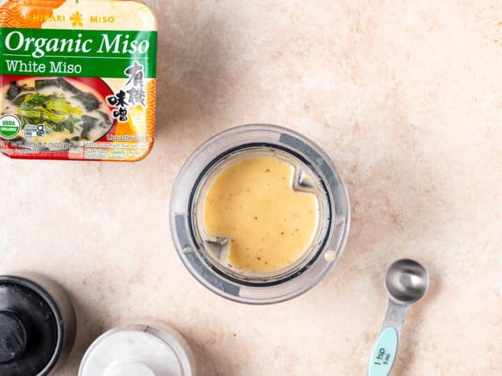 Creamy miso vinaigrette blended in a small blender cup with white miso paste nearby.