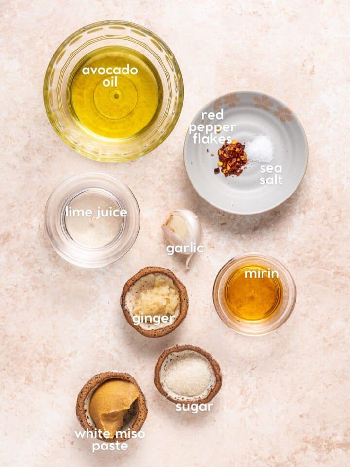 Ingredients for a creamy dressing including white miso paste, avocado oil, mirin, garlic, ginger, sugar, red pepper flakes and salt.