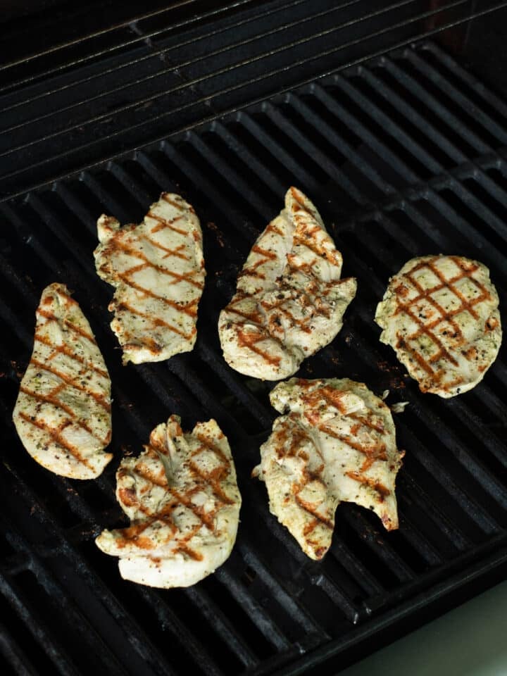 Chicken cutlets with golden brown grill marks cooking on a grill