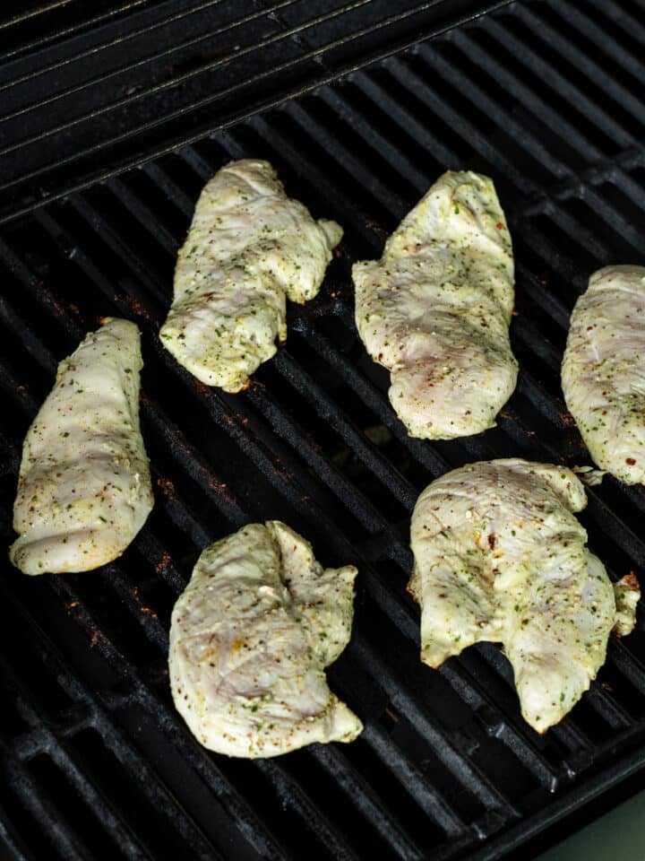 Thin-sliced chicken breast cooking on grill grates