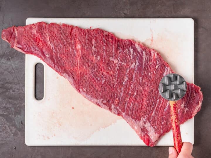 Tenderizing skirt steak with a meat mallet.