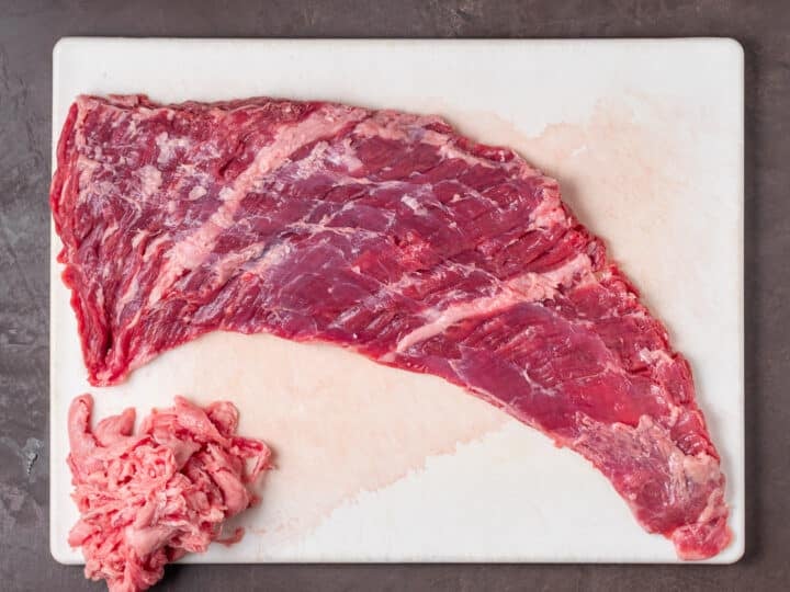 Raw steak on a cutting board with excess fat trimmed in the corner.