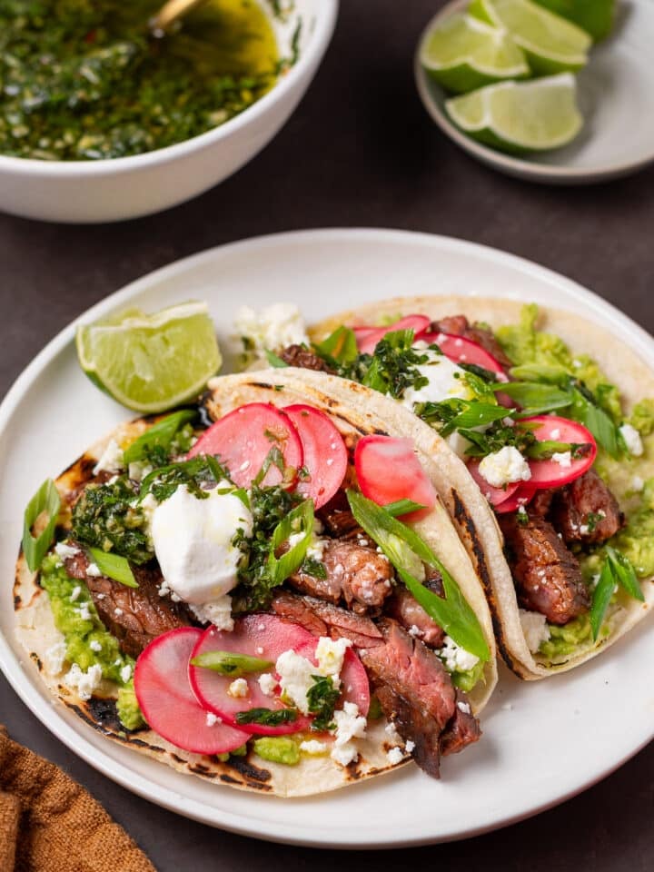 Skirt steak tacos with mashed avocado, pickled radishes, queso fresco, green onions, sour cream and cilantro chimichurri.