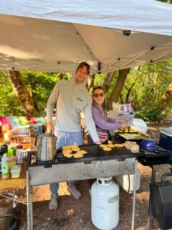 Erica and Ka-La preparing egg and cheese breakfast sandwiches on camping stove