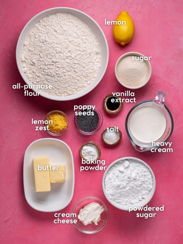 Labeled ingredients for scones and frosting arranged including butter, cream cheese, salt, baking powder, heavy cream, all purpose flour, and vanilla extract.