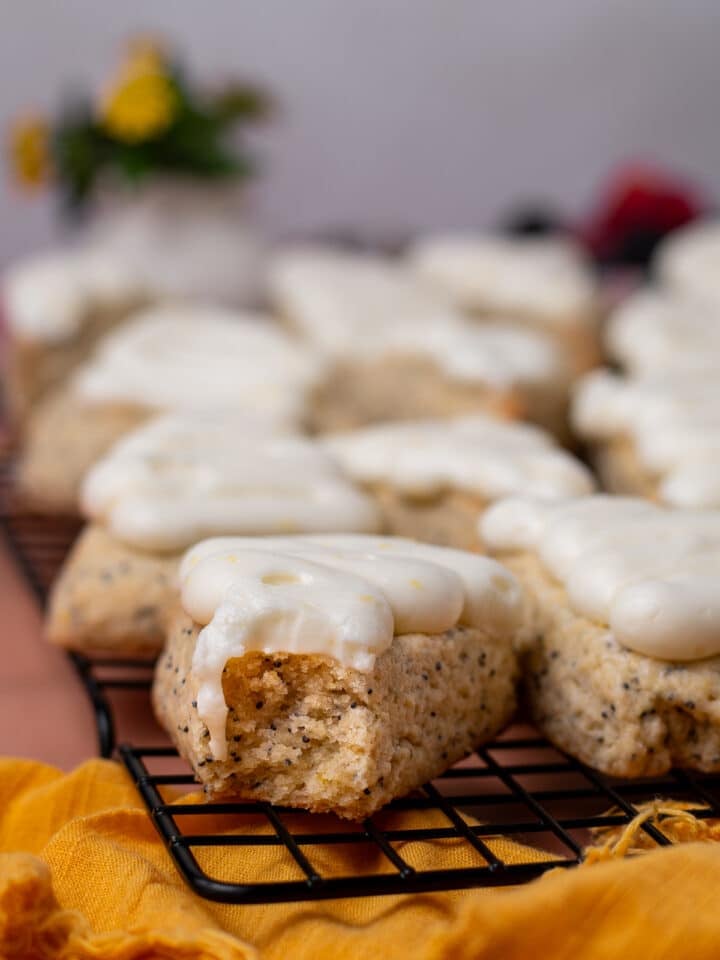 Lemon poppyseed scone with a bite taken out, showing the soft crumb beneath the cream cheese frosting.
