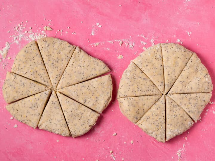 Two rounds of lemon poppyseed scone dough cut into eight wedges each.