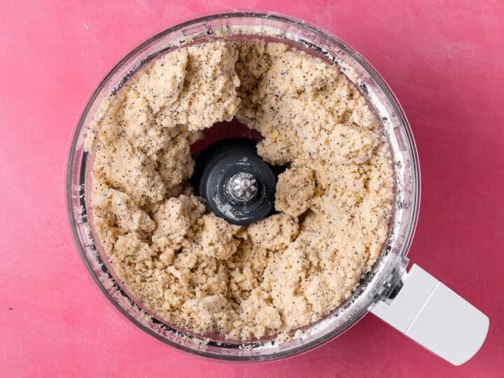 Lemon poppyseed scone dough coming together in the bowl of a food processor.